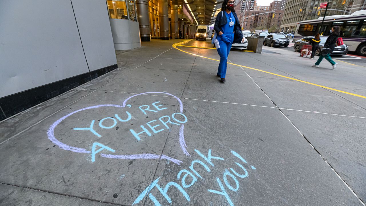 A nurse walks near a message written in chalk outside a New York City hospital during the coronavirus pandemic.