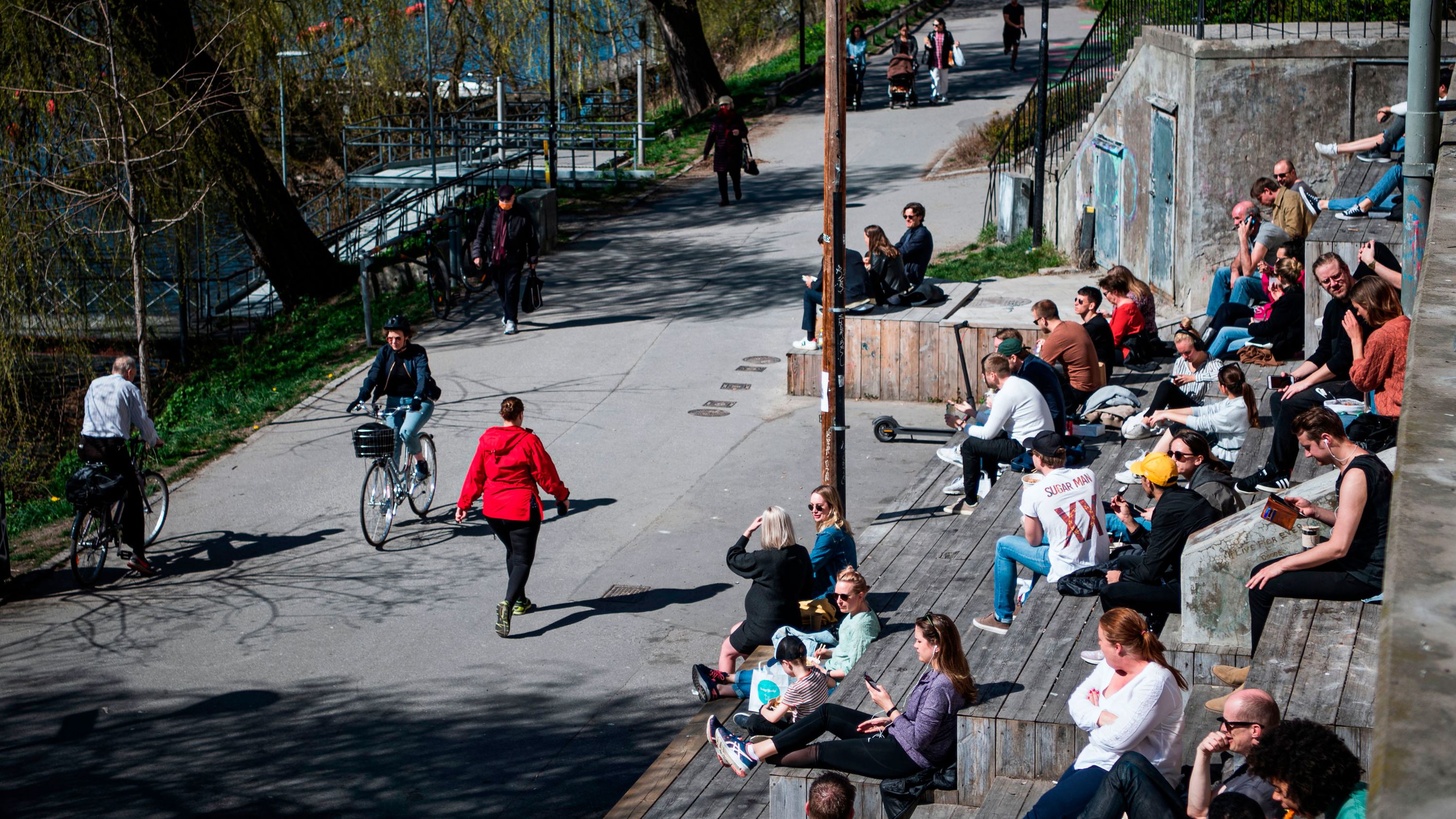 People enjoy the warm spring weather as they sit by the water at Hornstull in Stockholm on April 21 during the COVID-19 pandemic. 