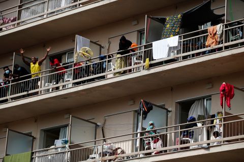 Migrants wave from balconies at a hotel in Kranidi, Greece, on April 21, 2020. The shelter, which hosts 470 asylum seekers, was placed in isolation after a pregnant resident tested positive for the novel coronavirus.