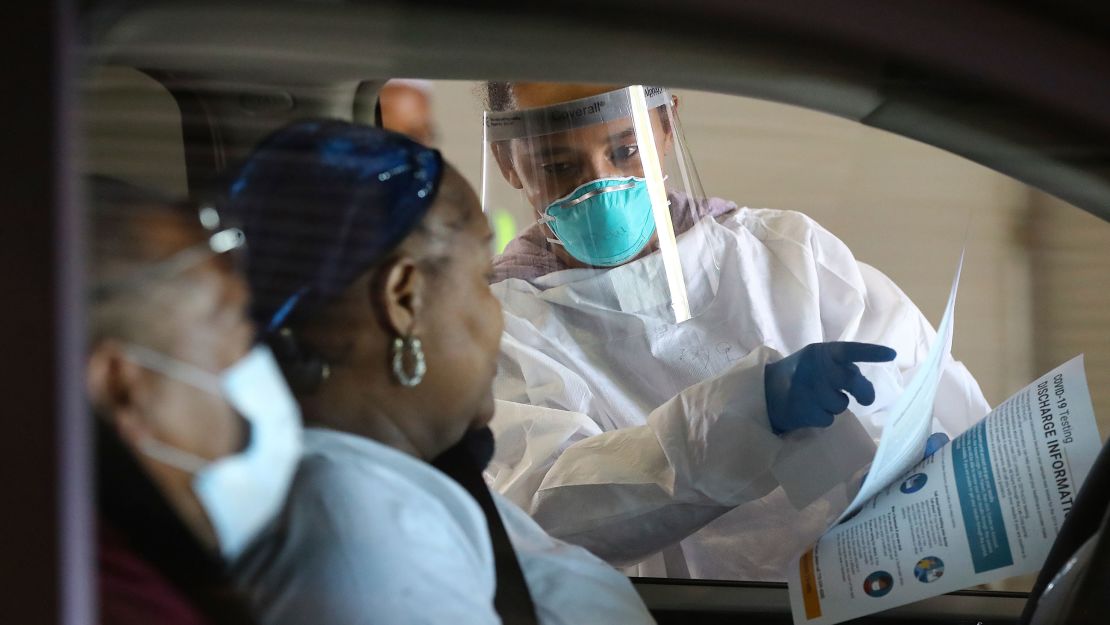Emory Hospital RN Aisha Bennett talks with a man and woman before taking nasal swabs at a drive-through COVID-19 testing site on April 16, 2020, in Conyers, Georgia.