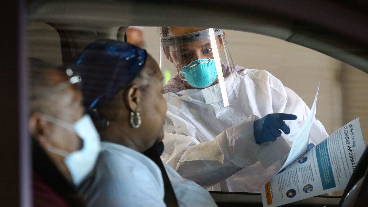 Emory Hospital RN Aisha Bennett talks with a man and woman before taking nasal swabs at a drive-through COVID-19 testing site on April 16, 2020, in Conyers, Georgia. 
