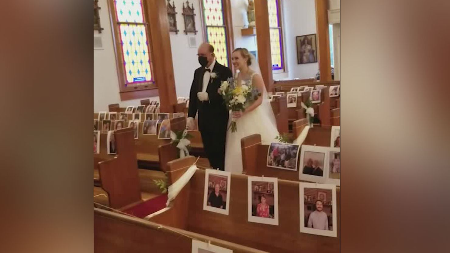 Clare Keefer is walked down the aisle by her father in the church, decorated with pictures of their guests.