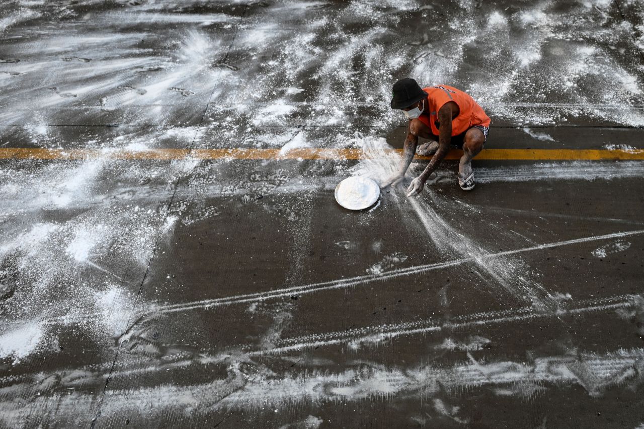A volunteer in Yangon, Myanmar, spreads calcium oxide on a road to help prevent the spread of the coronavirus on April 22, 2020.