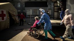 A health worker pushes a woman on a wheelchair towards a triage tent for suspected COVID-19 patients outside the Santa Maria Hospital in Lisbon on April 2, 2020. - The Portuguese face at least another two weeks in lockdown after the government decided to extend confinement measures as deaths from the COVID-19 epidemic near 200. (Photo by PATRICIA DE MELO MOREIRA / AFP) (Photo by PATRICIA DE MELO MOREIRA/AFP via Getty Images)