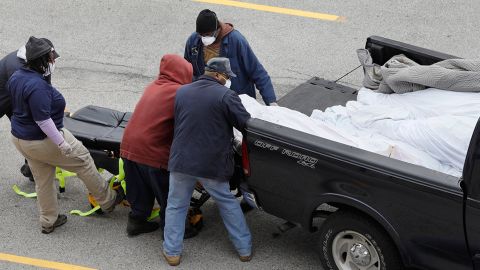 Workers assist the driver of the pickup truck (far right, with back to camera) as he pulls a body from the back of the truck and onto a gurney, in an area near the Joseph W. Spellman Medical Examiner Building on April 19.