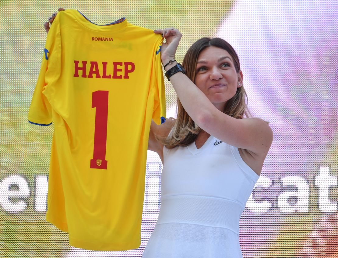Halep holds up a Romanian national football team jersey presented to her by the Romanian Football Federation,