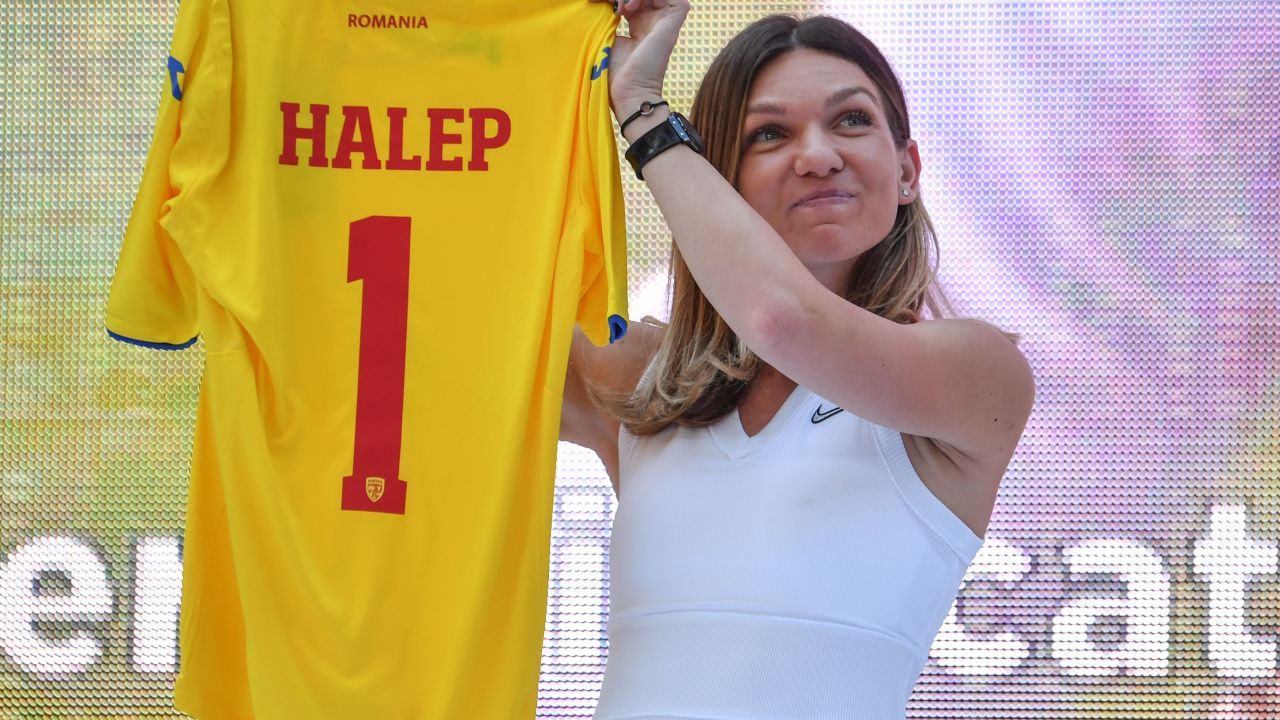 Halep holds up a Romanian national football team jersey presented to her by the Romanian Football Federation,