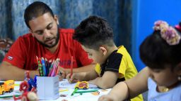 An Iraqi father, Mustafa C., is seen with his children, Rukayye and Ali, who are painting to draw attention to the novel coronavirus during a day of quarantine in Baghdad, Iraq, on April 18, 2020.