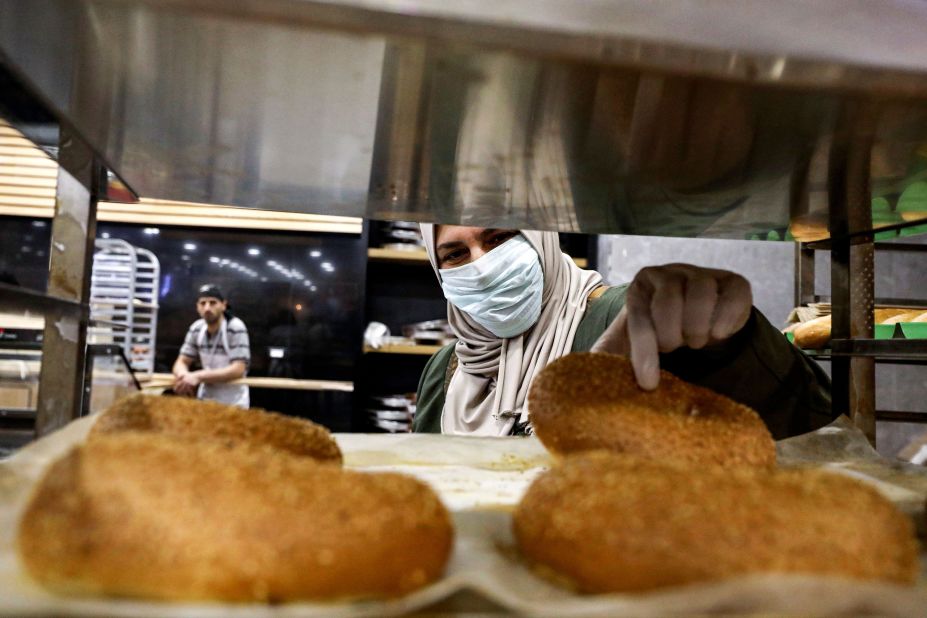 A woman in Hebron, West Bank, picks out freshly baked pastries as she shops for groceries before the start of Ramadan.