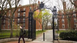 A pedestrian wearing a protective mask exits Harvard Yard on the closed Harvard University campus in Cambridge, Massachusetts, U.S., on Monday, April 20, 2020. College financial aid offices are bracing for a spike in appeals from students finding that the aid packages they were offered for next year are no longer enough after the coronavirus pandemic cost their parents jobs or income. Photographer: Adam Glanzman/Bloomberg via Getty Images