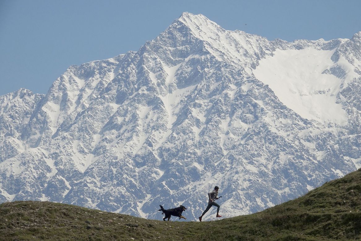 A man and his dog run in the Indian village of Jalot, near the Dhauladhar mountain range, on Wednesday, April 22.