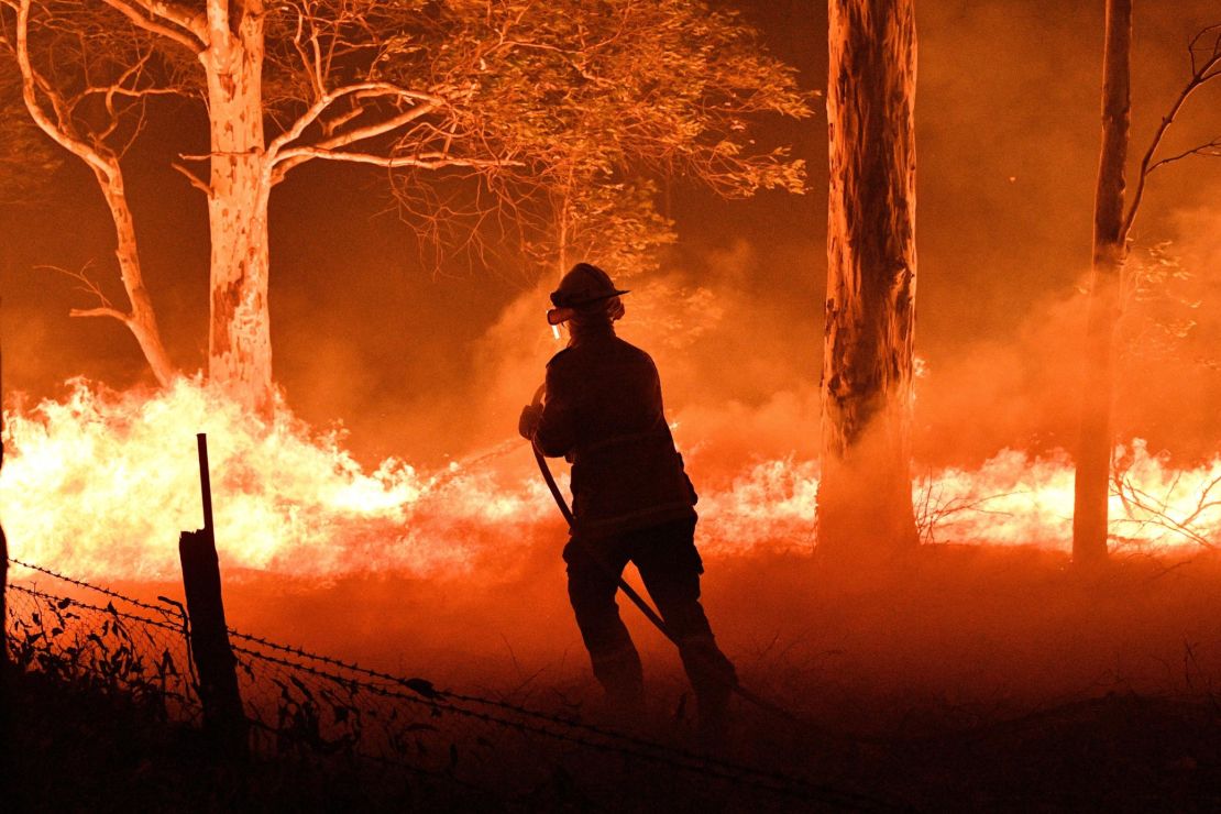 A firefighter hoses down trees and flying embers from bushfires in New South Wales.