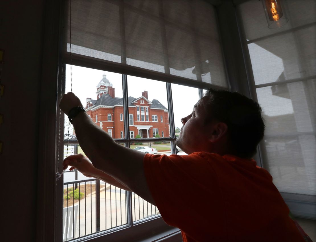 Brian Lambert, owner of a coffee and sweets shop in Forsyth, Georgia, opens the windows of his business as he gets ready to reopen next week.