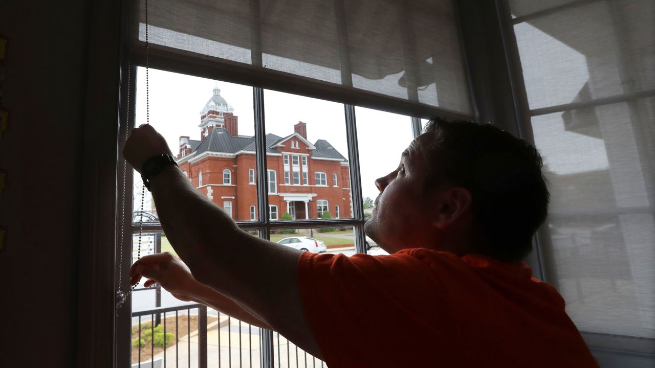 Brian Lambert, owner of a coffee and sweets shop in Forsyth, Georgia, opens the windows of his business as he gets ready to reopen next week. 