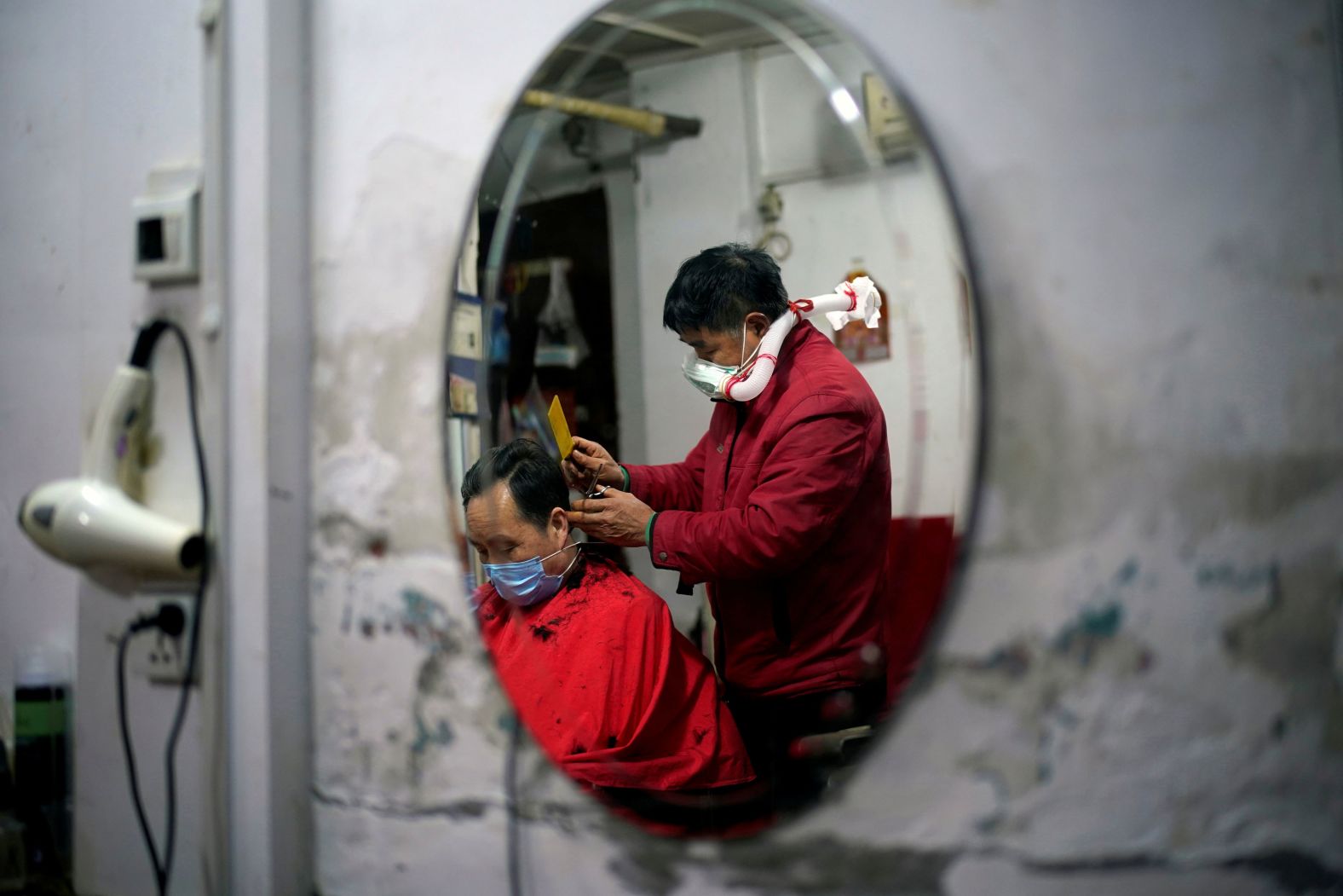 Barber Yang Guangyu cuts a client's hair in Wuhan, China, on April 11 while wearing protective gear assembled from a water bottle, mask and plastic pipe. The first city in the world to go into lockdown — and the epicenter of the global coronavirus outbreak — is <a  target="_blank">slowly returning to normal.</a>