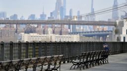 A man sits alone on a bench overlooking part of the Manhattan skyline amid the coronavirus pandemic on April 21 in the Brooklyn Borough of New York City. 