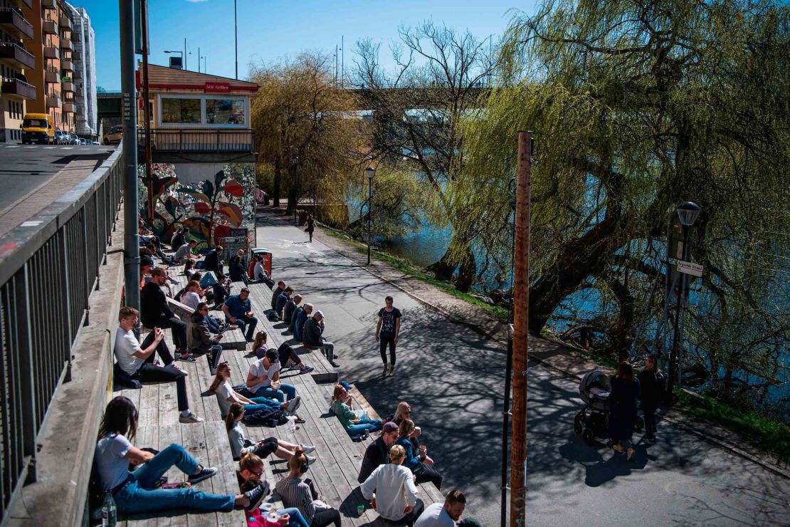 People enjoy the warm spring weather as they sit by the water at Hornstull in Stockholm on April 21.