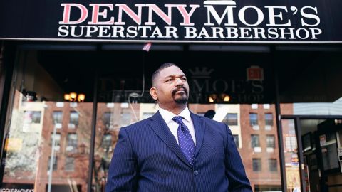 Dennis "Denny Moe" Mitchell, 54, stands outside of Denny Moe's Superstar Barbershop in Harlem, New York in an undated photo.