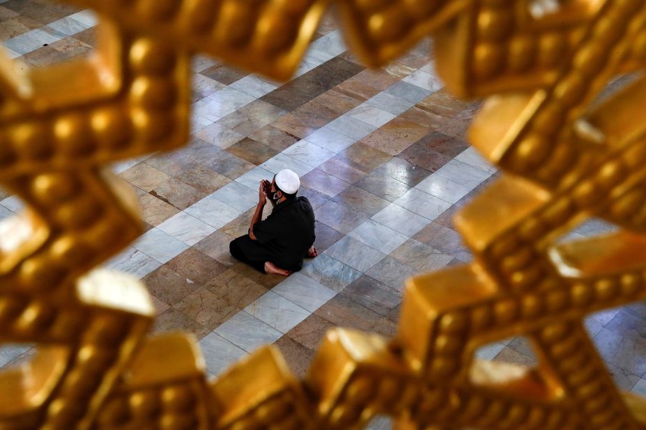 A Muslim man wearing a protective face mask prays at a mosque in Bangkok, Thailand.