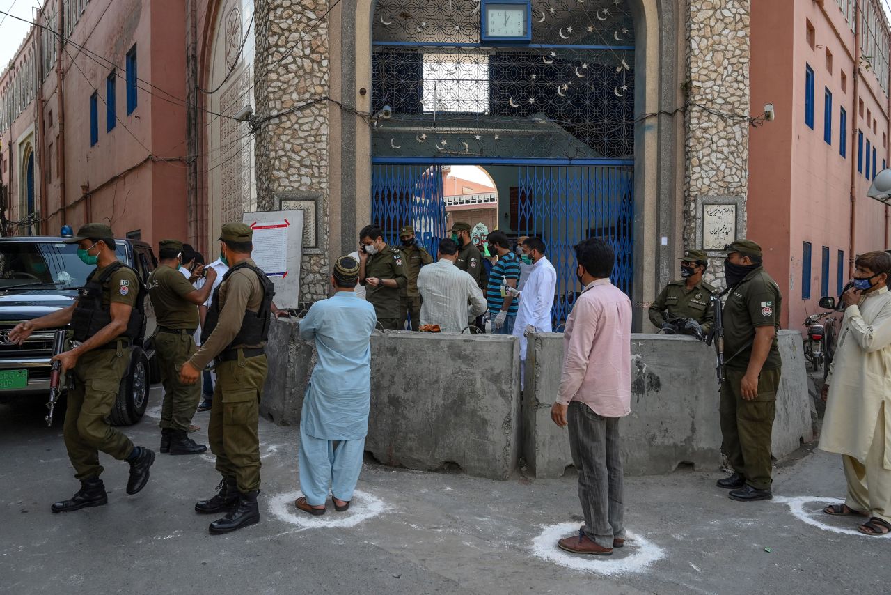 Security personnel stand guard and people spread out before entering a mosque in Lahore, Pakistan, on April 24.