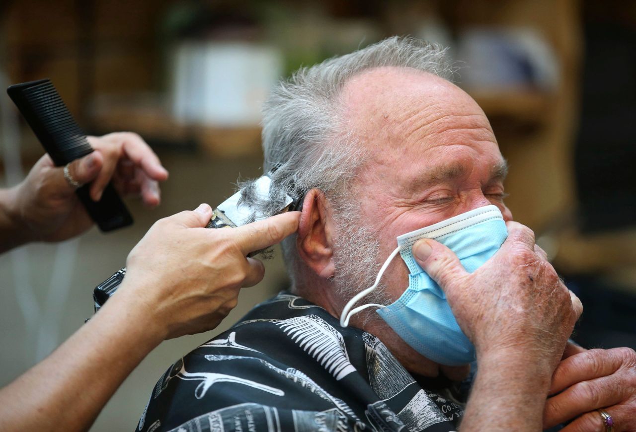 A man covers his face with a mask while getting a haircut at The Barber Shop in Broken Arrow, Oklahoma, on April 24. Personal-care businesses in the state have reopened for appointments.