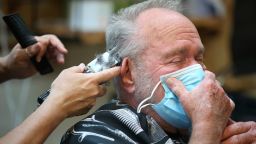 Lonnie Sullivan covers his face with a mask while getting a haircut at The Barber Shop in Broken Arrow, Okla., on Friday, April 24, 2020. The shop was among several allowed to reopen in a loosening of coronavirus-related restrictions. (Matt Barnard/Tulsa World via AP)