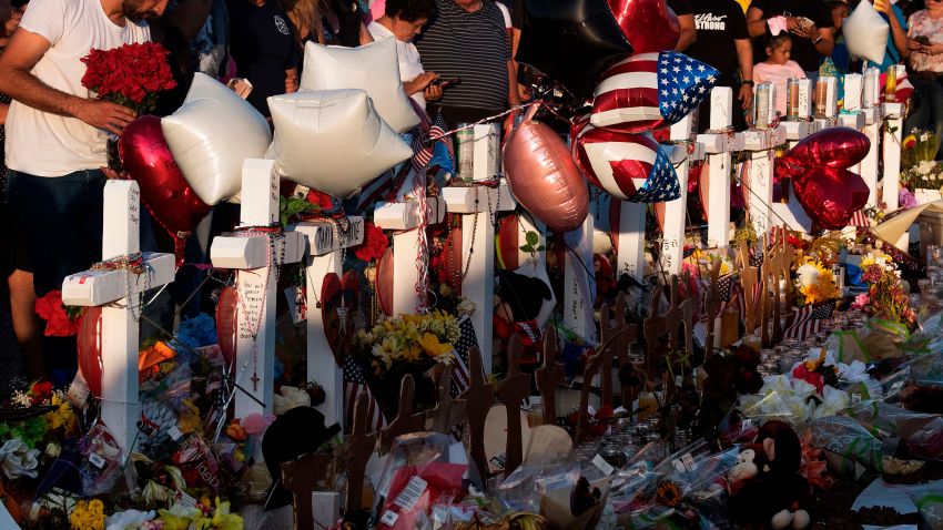 People pray and pay their respects at the makeshift memorial for victims of the shooting that left a total of 22 people dead at the Cielo Vista Mall WalMart (background) in El Paso, Texas, on August 6, 2019. - US President Donald Trump on Monday urged Republicans and Democrats to agree on tighter gun control and suggested legislation could be linked to immigration reform after two shootings left 30 people dead and sparked accusations that his rhetoric was part of the problem. "Republicans and Democrats must come together and get strong background checks, perhaps marrying this legislation with desperately needed immigration reform," Trump tweeted as he prepared to address the nation on two weekend shootings in Texas and Ohio. "We must have something good, if not GREAT, come out of these two tragic events!" Trump wrote. (Photo by Mark RALSTON / AFP)        (Photo credit should read MARK RALSTON/AFP via Getty Images)