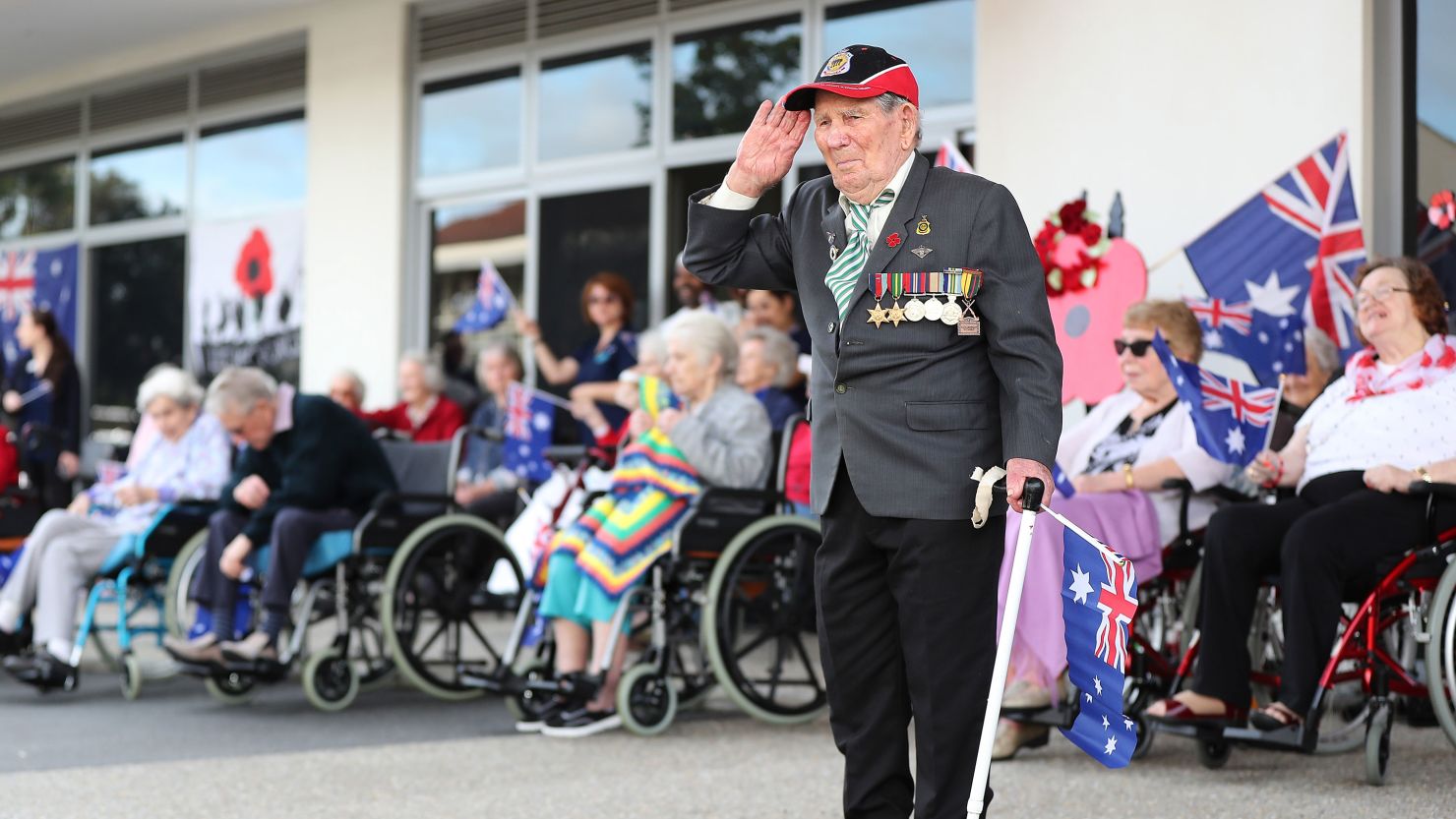 War veteran Tom Newby, 100,  stands to attention as families and friends perform a drive-by parade on April 25, 2020 in Perth, Australia. 