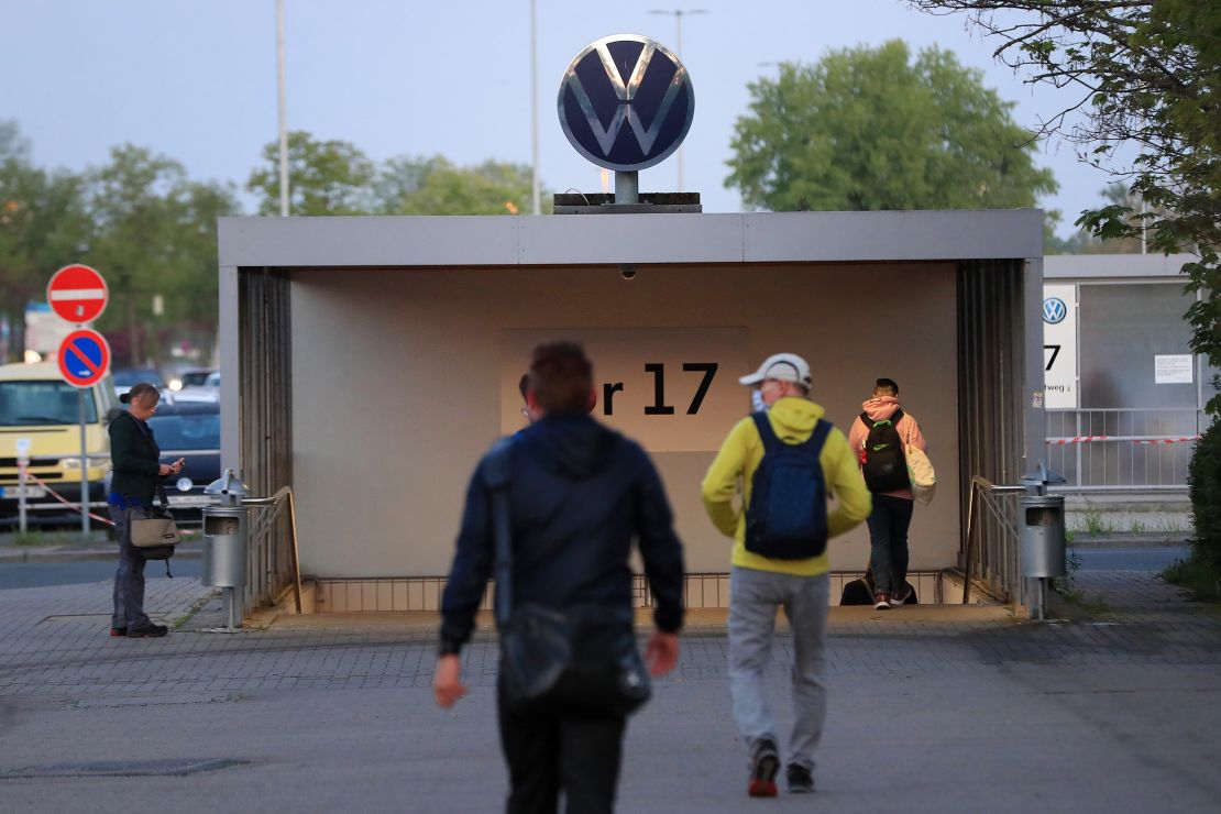 Employees walk towards an entrance gate at the Volkswagen plant in Wolfsburg, Germany, on April 27, 2020. 