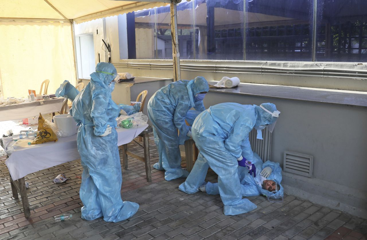 Health workers at a coronavirus testing center in New Delhi attend to a colleague who fainted due to exhaustion on April 27, 2020. 