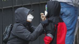 A woman adjusts her child's protective mask as they wait in line to be screened for COVID-19 at Gotham Health East New York, Thursday, April 23, 2020, in the Brooklyn borough of New York. (AP Photo/Frank Franklin II)