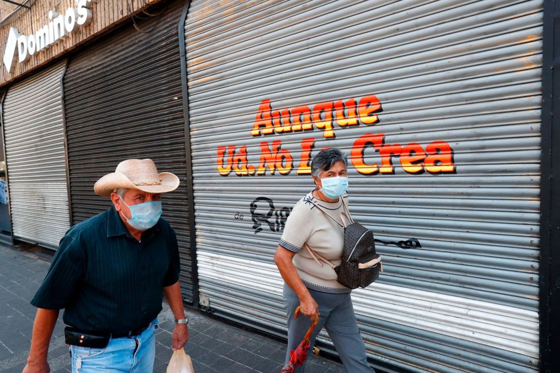 People walk by a closed store during the pandemic in Guadalajara City, Mexico.