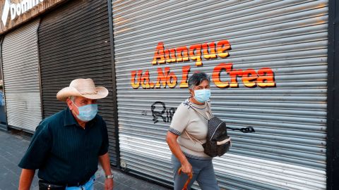 People walk by a closed store during the pandemic in Guadalajara City,  Mexico.