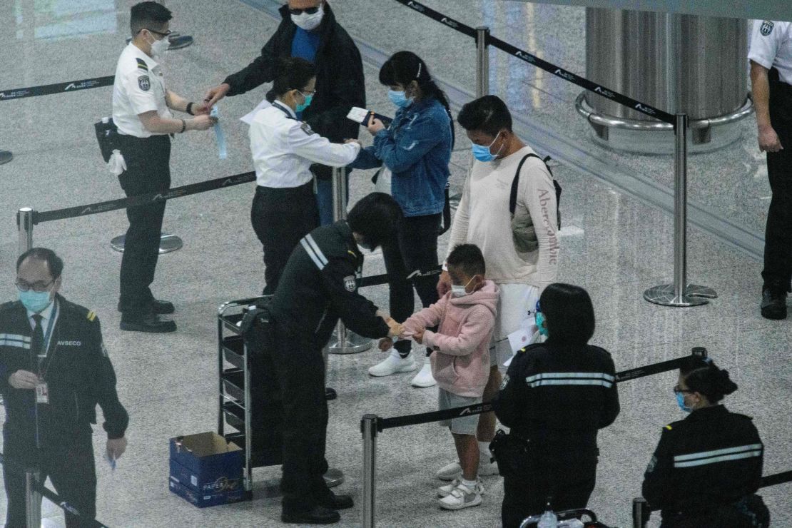 A photo taken through thick glass shows passengers (center) wearing face masks as a precautionary measure against the coronavirus as they receive quarantine tracking wrist bands at Hong Kongs international airport on March 19.