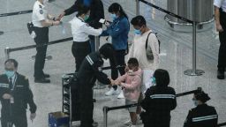 A photo taken through thick glass shows passengers (C) wearing face masks as a precautionary measure against the COVID-19 coronavirus as they receive quarantine tracking wrist bands at Hong Kongs international airport on March 19, 2020. - On March 18, Hong Kong authorities began ordering all arrivals from overseas to wear electronic bracelets, connected to an app to mark your location, and two weeks self-quarantine. (Photo by ANTHONY WALLACE / AFP) (Photo by ANTHONY WALLACE/AFP via Getty Images)