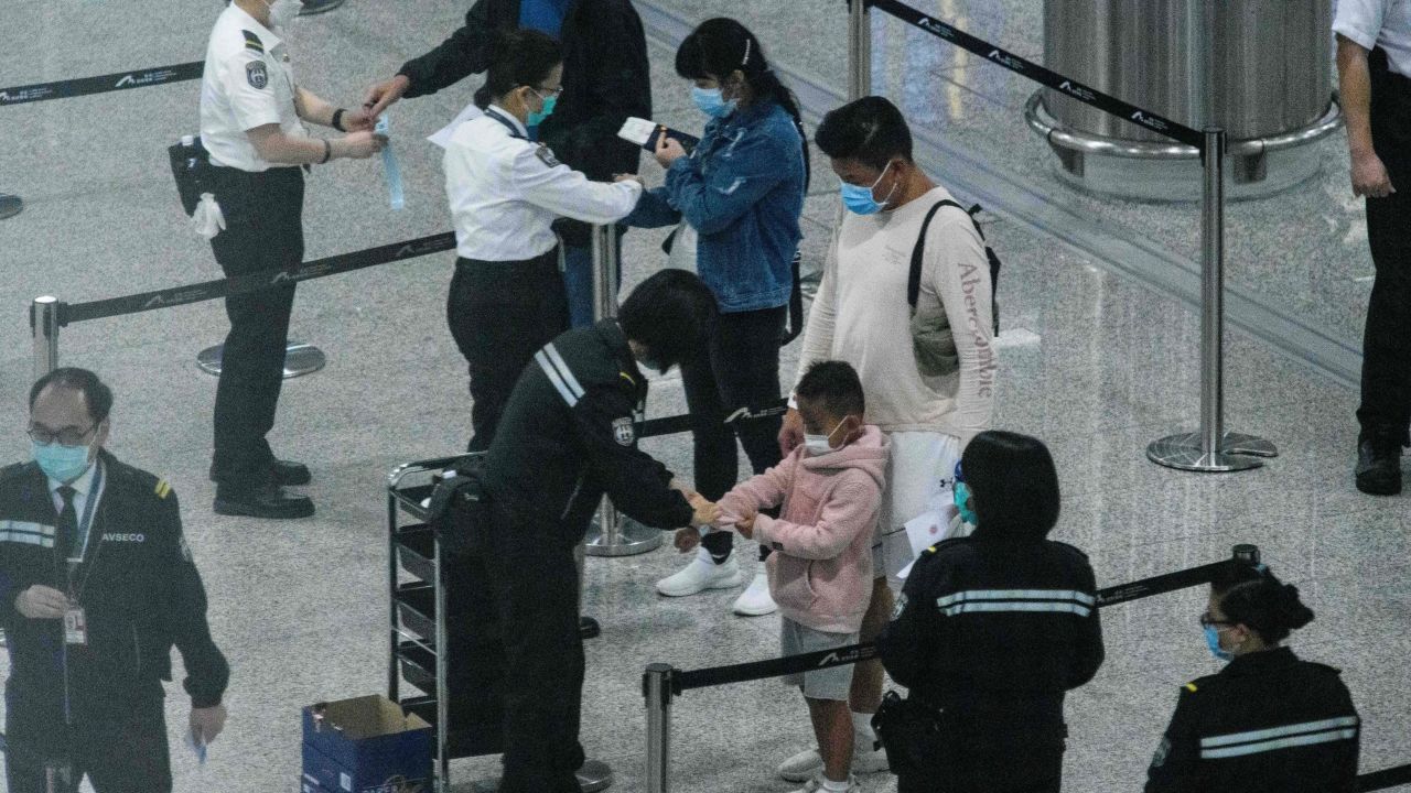 A photo taken through thick glass shows passengers (center) wearing face masks as a precautionary measure against the coronavirus as they receive quarantine tracking wrist bands at Hong Kongs international airport on March 19.