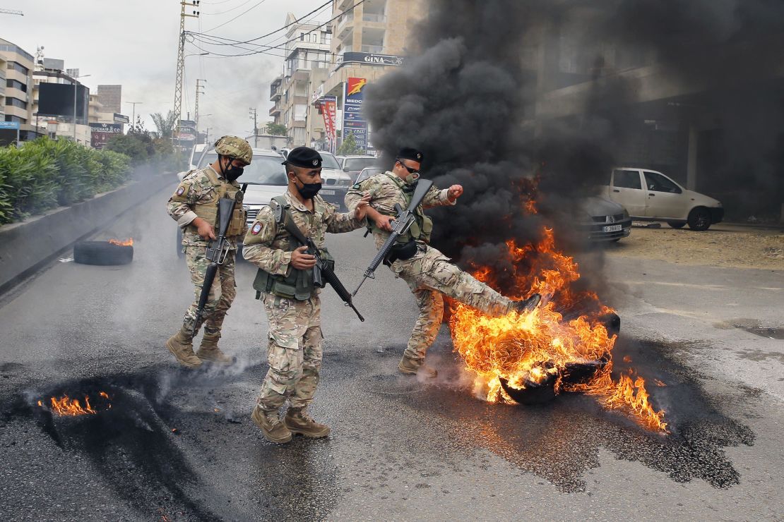 Lebanese soldiers remove burning tires placed by anti-government protesters to block a road.