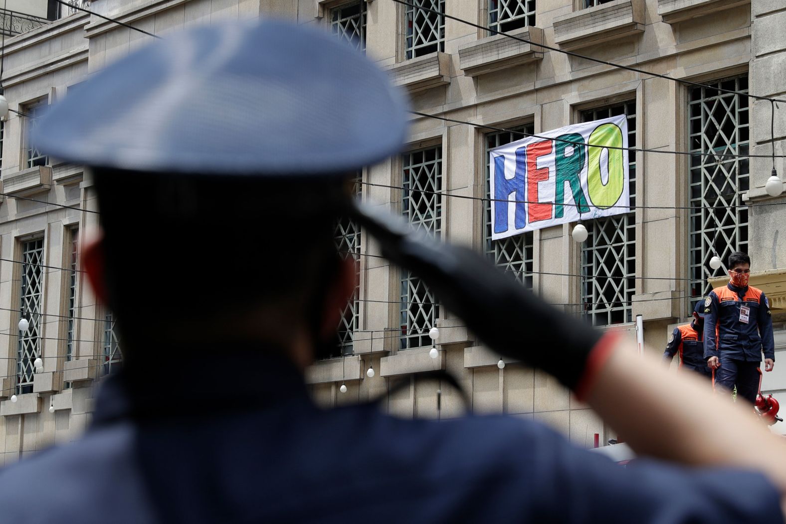 A security guard salutes as residents clap and sing from their windows in Manila, Philippines, on April 12.