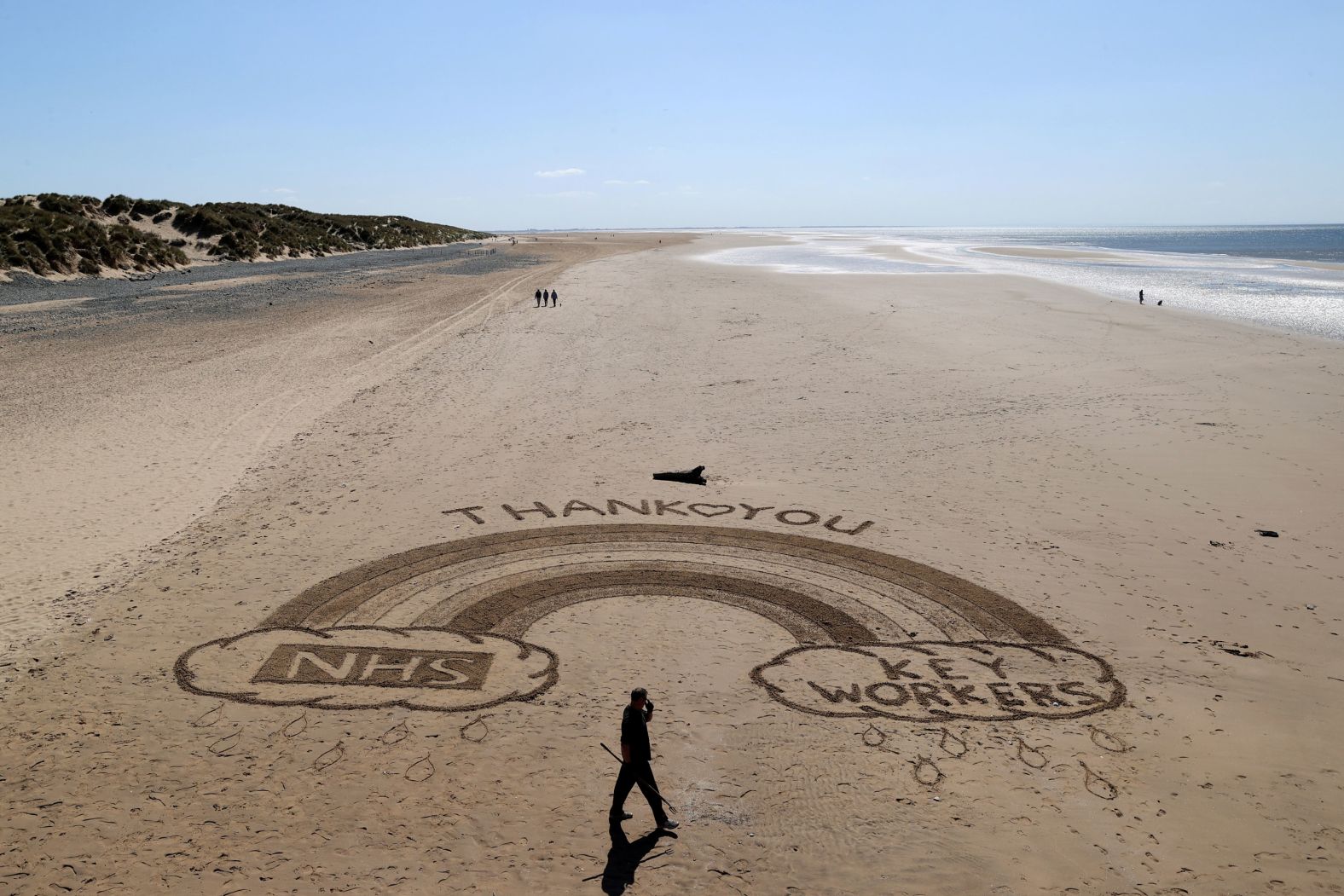 Ben from the Sandymental art team works on a sand drawing at Lytham St. Annes, a seaside resort in London, on April 20.