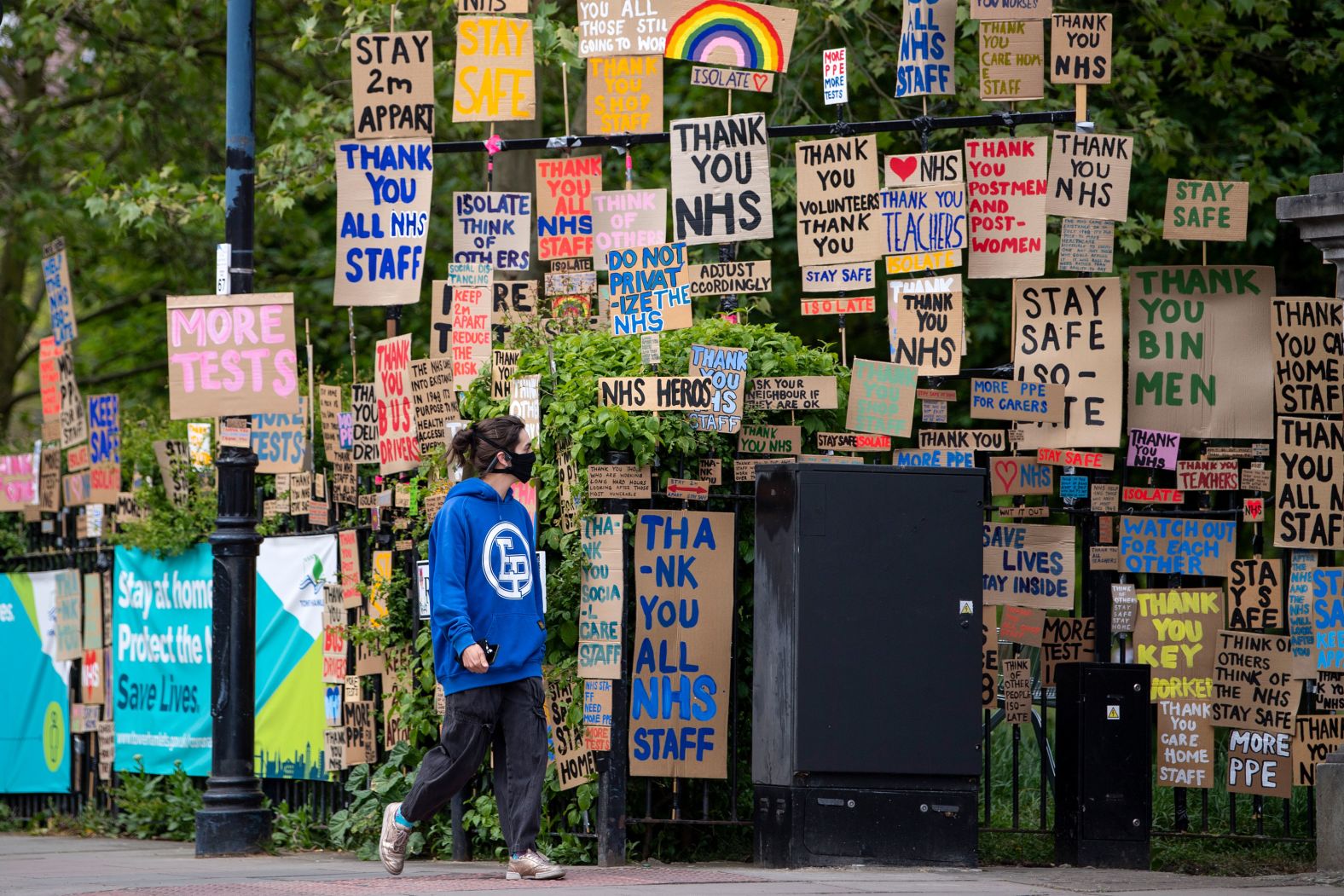A woman in London walks past signs supporting essential workers on April 25.