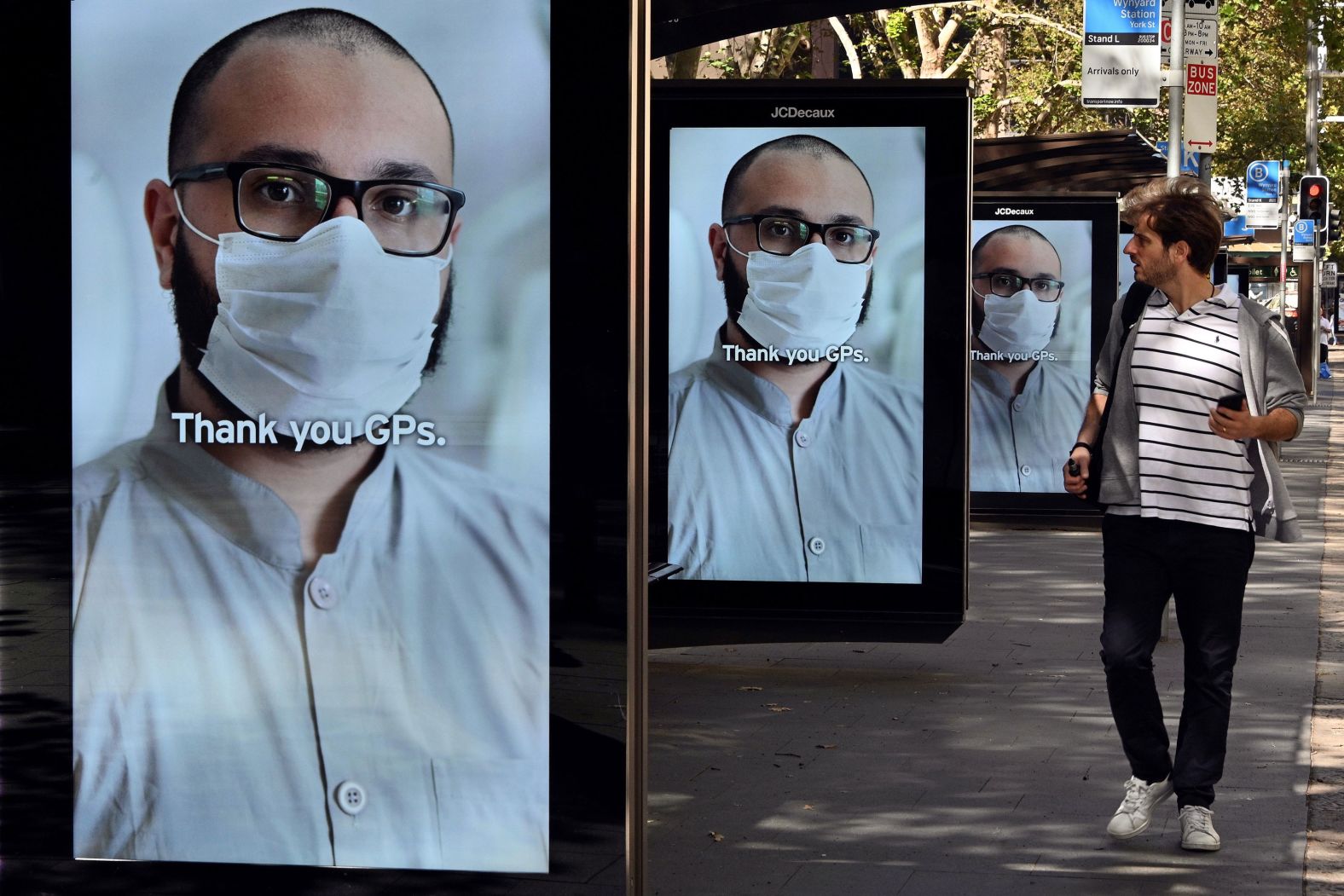 A man walks past bus-stop advertising boards that thanked health-care workers in Sydney on April 15.