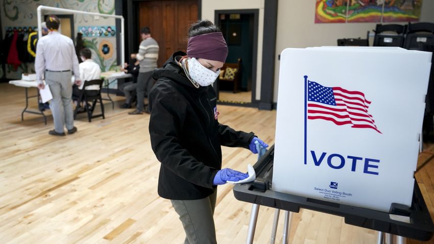 Shanon Hankin, cleans a voter booth after it was used for voting at the Wil-Mar Neighborhood Center Tuesday,  April 7, 2020 in Madison, Wis.  Voters across the state are ignoring a stay-at-home order in the midst of a pandemic to participate in the state's presidential primary election. (Steve Apps/Wisconsin State Journal via AP)