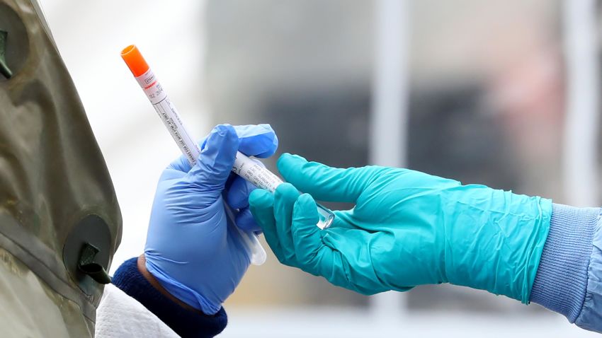 Medical professionals pass each other a coronavirus test at a drive-thru testing site at Cambridge Health Alliance Somerville Hospital on April 28, 2020 in Somerville, Massachusetts.