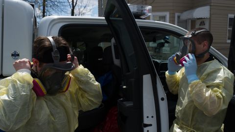 Paramedics Alex Storzillo and Jim Incorvaia adjust their respirators before entering a house.
