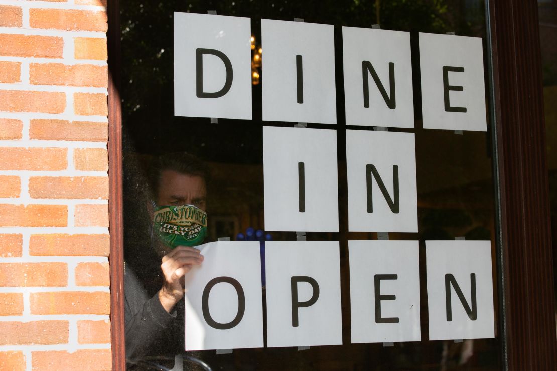 A man hangs up signs to to promote dine-in service available at a restaurant in Brookhaven, Georgia, on April 27.