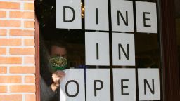 A man hangs up signs to to promote dine in service now available at a restaurant in Brookhaven, Georgia on April 27.  Gov. Brian Kemp has allowed some non-essential businesses to start re-opening in Georgia amid the COVID-19 Pandemic.  
