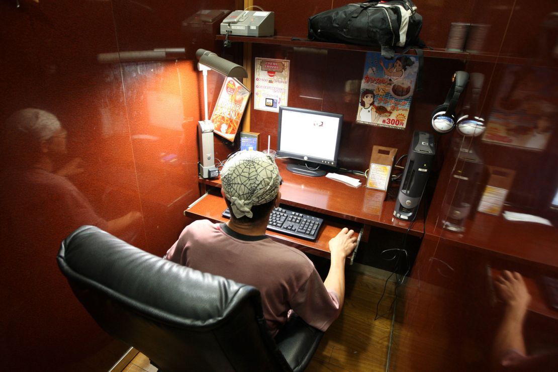 A man relaxes in his private booth where he will spend the night, in one of Tokyo's many 24-hour internet cafes, which provide the capital's homeless with a roof over their heads.