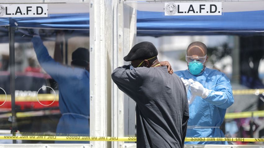 LOS ANGELES, CALIFORNIA - APRIL 21: A man is asked to cough into his arm as part of testing for COVID-19, by a member of the Los Angeles Fire Department wearing personal protective equipment (PPE) in Skid Row, amidst the coronavirus pandemic on April 21, 2020 in Los Angeles, California. 43 people tested positive for COVID-19 at one nearby Skid Row homeless shelter. (Photo by Mario Tama/Getty Images)