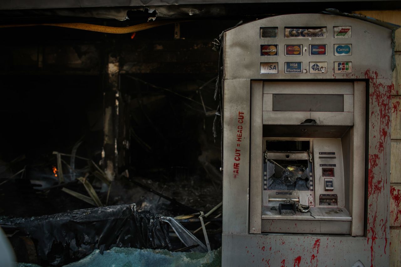 Red paint is seen on a burned ATM on Tuesday. The paint reads "hair cut = head cut."