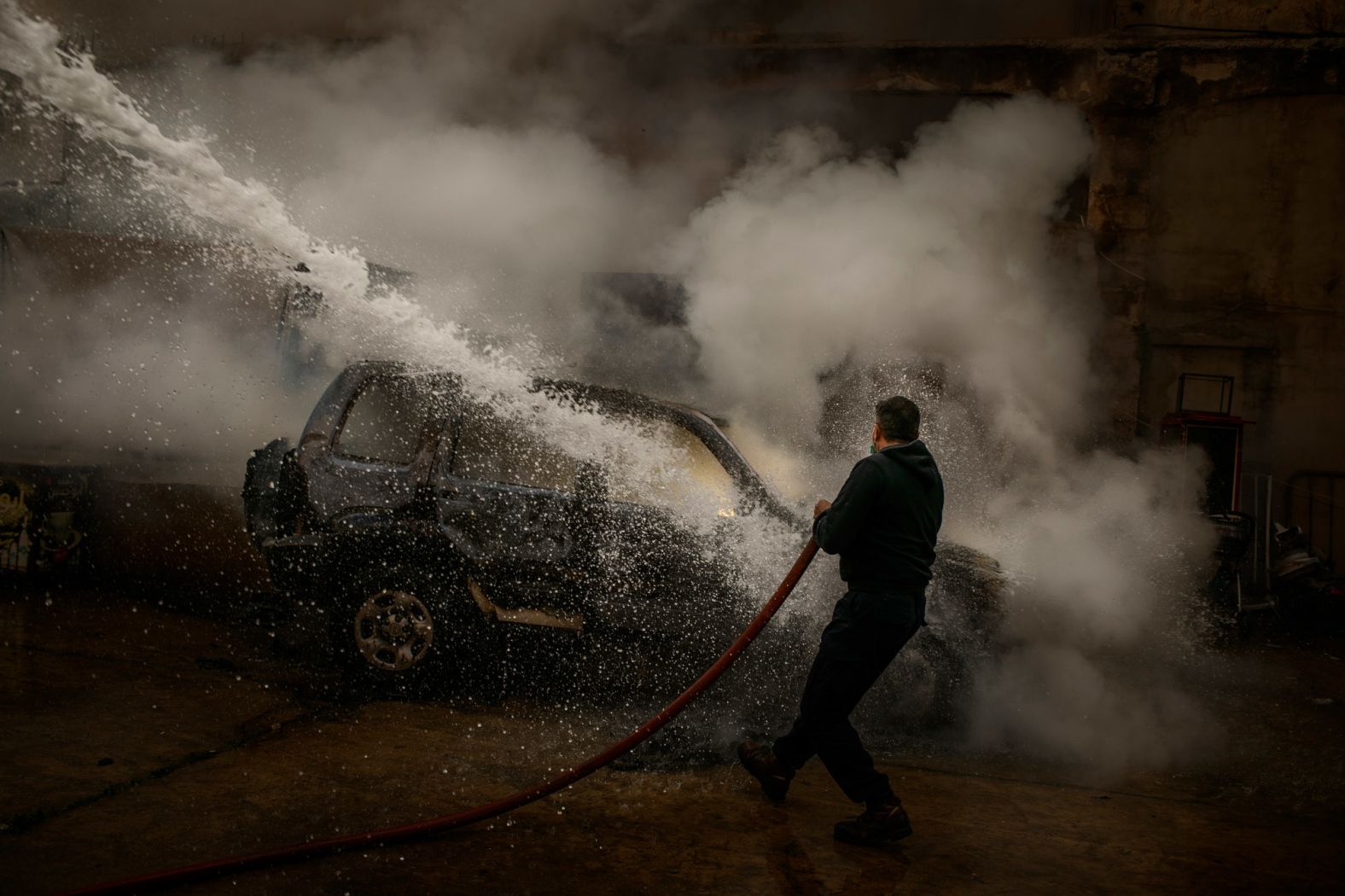 A member of the Lebanese Civil Defense extinguishes a police car that was set on fire by protesters in Tripoli.